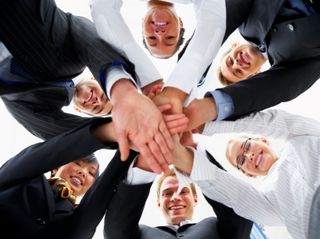 Here's an alt tag for the image: Teamwork: hands clasped in a circle.