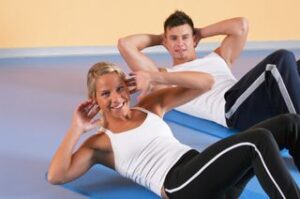 Here's an alt tag for the image: Smiling couple doing sit-ups together.