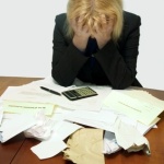 Here's an alt tag for the image: Stressed businesswoman overwhelmed by paperwork.