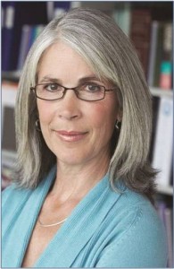 A woman with grey hair wearing glasses and smiling.