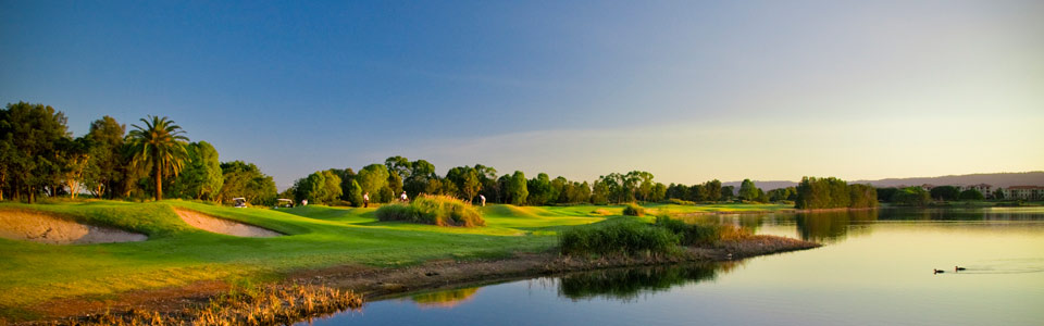 A golf course with trees and water in the background.