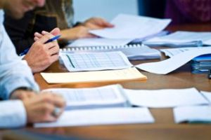 A group of people sitting at a table with papers.