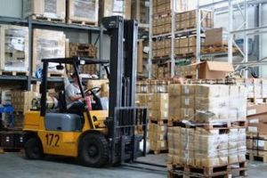 A forklift is in the middle of a warehouse filled with boxes.