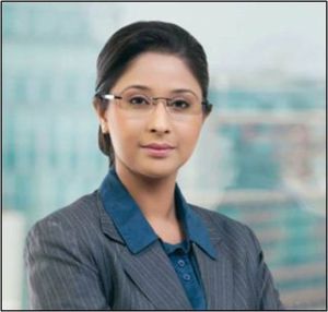 A woman in glasses and suit poses for the camera.