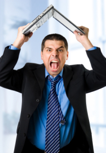 Here's an alt tag for the image: Angry businessman holding laptop overhead.