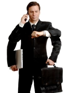 Here's an alt tag for the image: Busy businessman multitasking with phone, laptop, and briefcase.