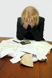 Here's an alt tag for the image: Stressed woman overwhelmed by paperwork.