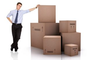 Here's an alt tag for the image: Businessman leaning on stack of boxes.