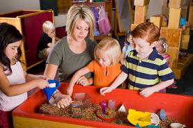 Here's an alt tag for the image: Teacher and preschoolers playing with sensory bin.