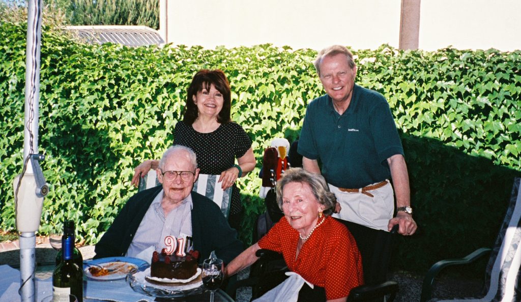 A group of people sitting around a table with cake.